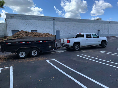 Trailer loaded with yard material beside a pickup truck in a parking lot